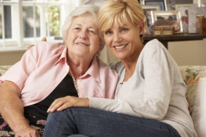 Adult Daughter Visiting Senior Mother Sitting On Sofa At Home